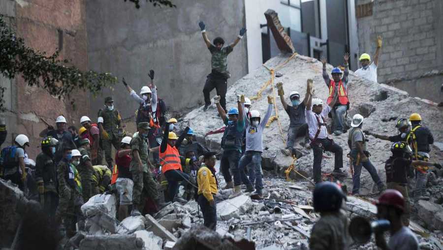 Rescuers raise hands for silence to listen for possible victims inside the rubble in Mexico City.