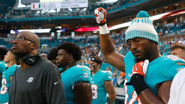 Miami Dolphins defensive end Robert Quinn (94) raises his right fist during the singing of the national anthem, before the team's NFL preseason football game against the Tampa Bay Buccaneers, Thursday, Aug. 9, 2018, in Miami Gardens, Fla.