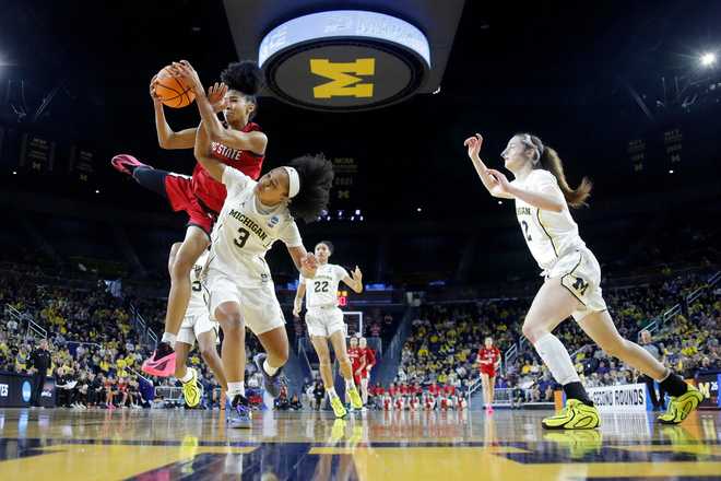 North Carolina State guard Qadence Samuels, top left, and Michigan guard Mila Holloway (3) battle for a rebound as Michigan guard Syla Swords, right, moves in during the first half in the second round of the NCAA college basketball tournament, Sunday, March 22, 2026, in Ann Arbor, Mich.