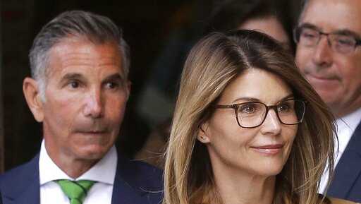 In this April 3, 2019, file photo, actress Lori Loughlin, front, and her husband, clothing designer Mossimo Giannulli, left, depart federal court in Boston after facing charges in a nationwide college admissions bribery scandal. Giannulli has been released from a California prison, Saturday, April 3, 2021, and is under home confinement following his imprisonment for his role in a college admissions bribery scheme. (AP Photo/Steven Senne, File)