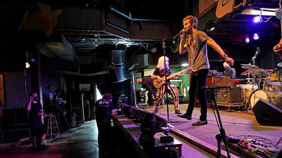 In this Oct. 26, 2020, photo, David Shaw, foreground, frontman for the band The Revivalists, performs with actor Harry Shearer as they record a video stream concert with the band Galactic, inside an empty Tipitina's music club, in New Orleans.