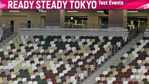 A support team member is seen in almost deserted spectators seats during an athletics test event for Tokyo 2020 Olympic Games at the National Stadium in Tokyo Sunday, May 9, 2021.