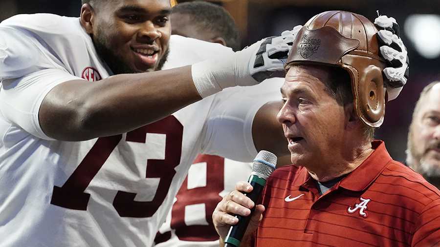 Alabama offensive lineman Evan Neal (73) places the leather helmet from the "Old Leather Helmet Torphy" on head coach Nick Saban's head after they defeated Miami in the Chick-fil-A Kickoff NCAA college football game Saturday, Sept. 4, 2021, in Atlanta. (AP Photo/John Bazemore)