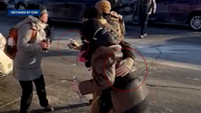 Video shows Alex Pretti holding a cell phone with another hand on a woman.