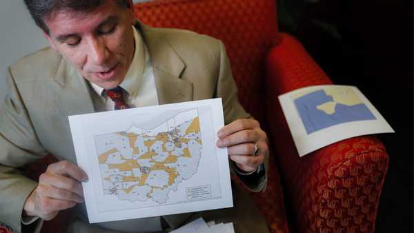 David Niven, a professor of political science at the University of Cincinnati holds a map displaying the wide disparity of Ohio congressional district office locations, with orange locations representing areas whose office are found outside it's own district's bounds, Thursday, April 11, 2019, in Cincinnati. Congressional Democrats nationwide had a good year in 2018, gaining 40 seats. But Republicans held fast with 75% of Ohio’s House seats, despite winning only 52% of Ohio’s congressional vote total. “Not a single seat has changed hands,” said Niven, who testified for those challenging Ohio’s map. “Not a single seat. The point of this map was to build a seawall against the storm, and it has held.” (AP Photo/John Minchillo)