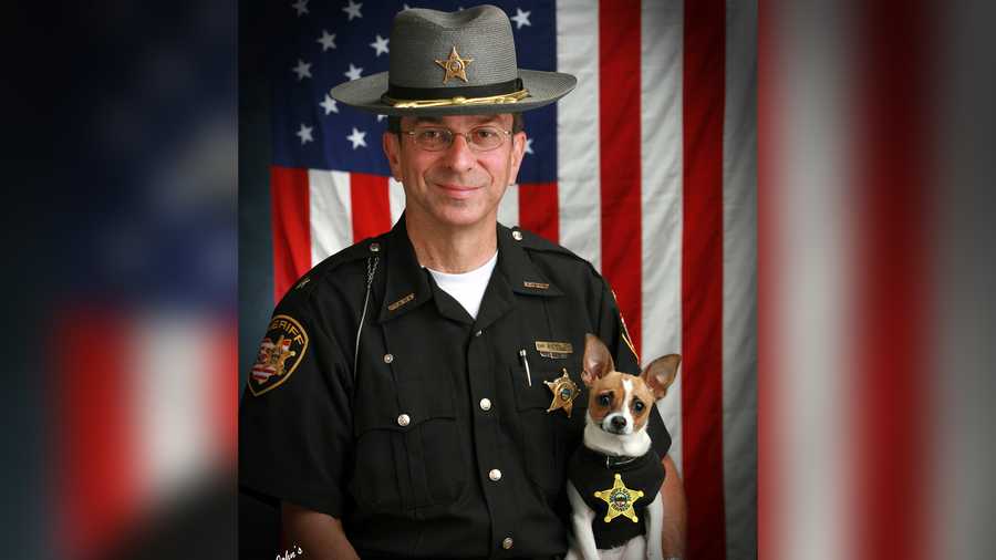 This 2006 image provided by John Hoffart shows then-Sheriff Dan McClelland and his small police dog Midge at the Geauga County, Ohio, sheriff's department. Both died on Wednesday, April 14, 2021.