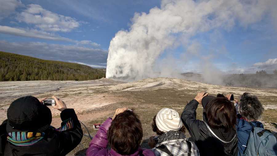 In this May 21, 2011, file photo, tourists photograph Old Faithful erupting on schedule late in the afternoon in Yellowstone National Park, Wyo. 