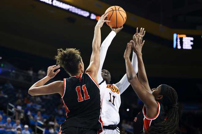 Princeton forward Taylor Charles (11) blocks a shot against Oklahoma State forward Achol Akot (11) as guard Fadima Tall, right, defends during the first half in the first round of the NCAA college basketball tournament, Saturday, March 21, 2026.
