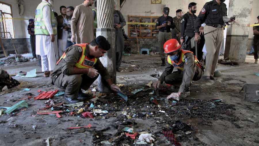 Rescue workers and police officers examine the site of bomb explosion in an Islamic seminary in Peshawar, Pakistan, Tuesday, Oct. 27, 2020.