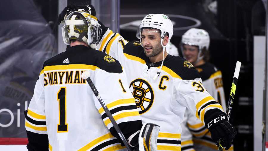 Boston Bruins' Patrice Bergeron, right, celebrates with goaltender Jeremy Swayman (1) after their teams victory against the Philadelphia Flyers, Tuesday, April 6, 2021, in Philadelphia. The Bruins won 4-2. (AP Photo)