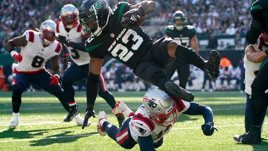 New York Jets running back James Robinson (23) is upended by New England Patriots cornerback Jack Jones (13) during the third quarter of an NFL football game, Sunday, Oct. 30, 2022, in New York.