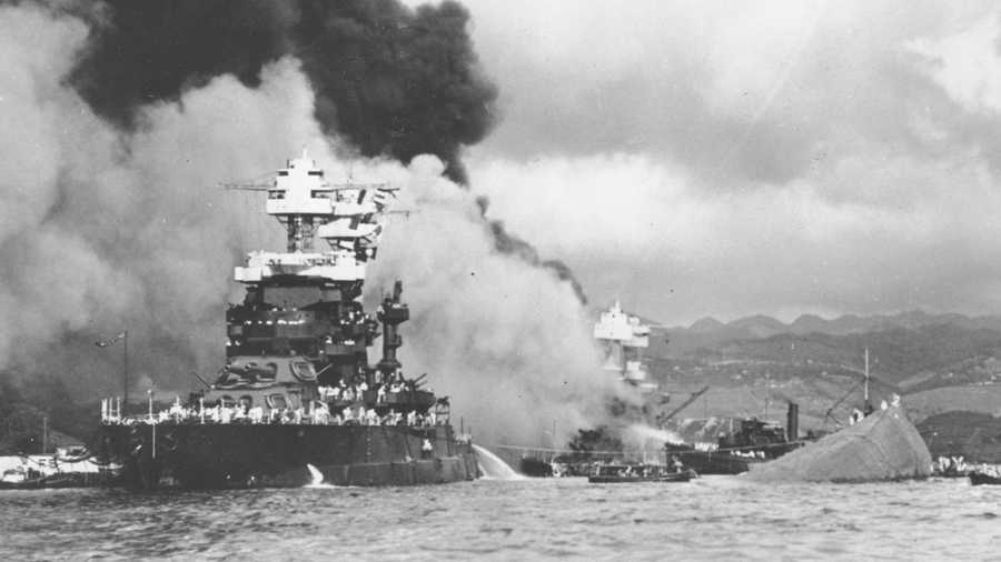 In this Dec. 7, 1941, file photo, part of the hull of the capsized USS Oklahoma is seen at right as the battleship USS West Virginia, center, begins to sink after suffering heavy damage, while the USS Maryland, left, is still afloat in Pearl Harbor, Oahu, Hawaii.