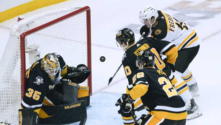 Boston Bruins' Trent Frederic, right, tries to bat the puck past Pittsburgh Penguins goaltender Tristan Jarry (35) during the first period of an NHL hockey game Tuesday, Nov. 1, 2022, in Pittsburgh.