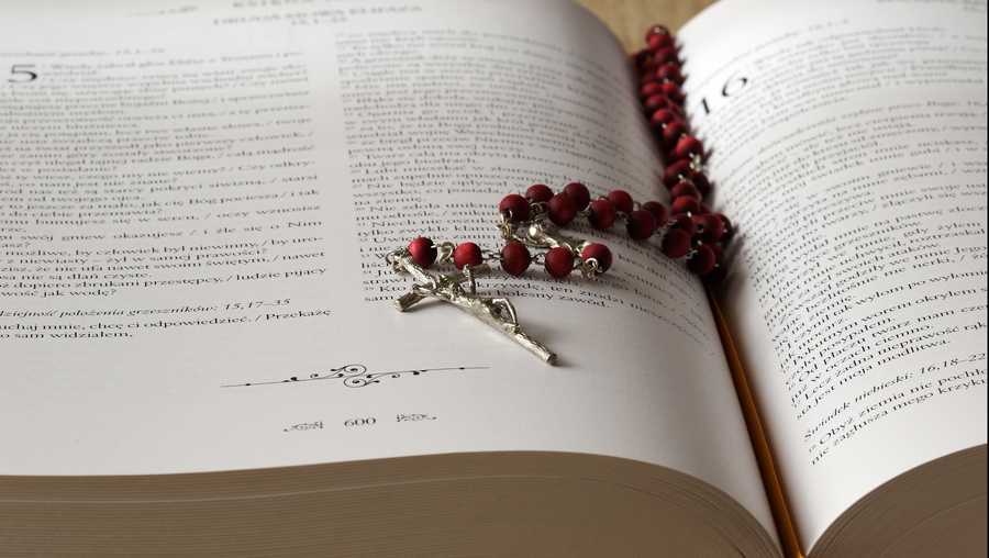 a rosary lies across an open bible.