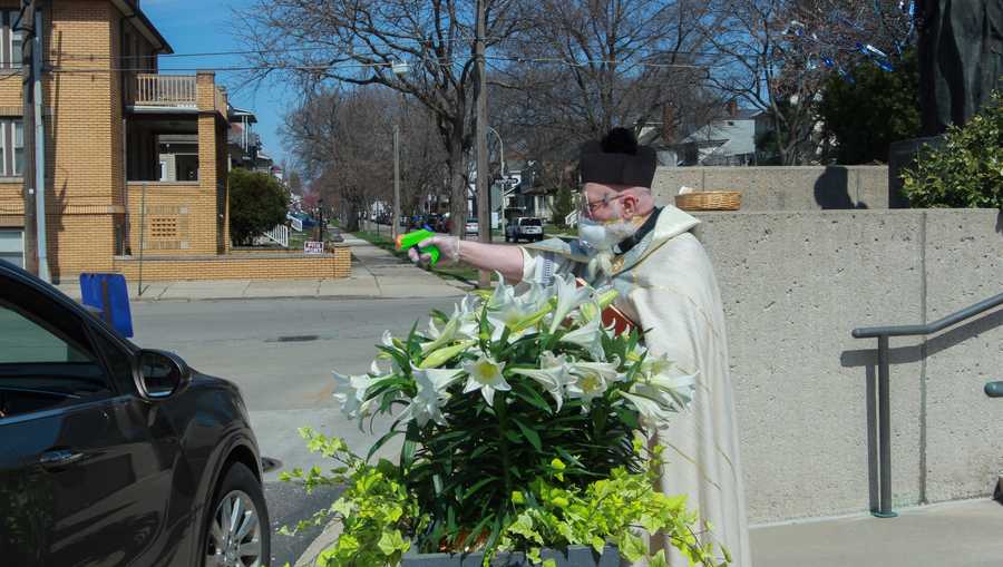 in this saturday, april 11, 2020 file photo, rev timothy pelc blesses easter baskets outside st ambrose church in grosse pointe park, mich pelc, wearing church vestments and protective gear, offered a prayer and sprayed holy water from a squirt gun instead of blessing baskets inside the church in a bid to maintain social distancing during the coronavirus pandemic
