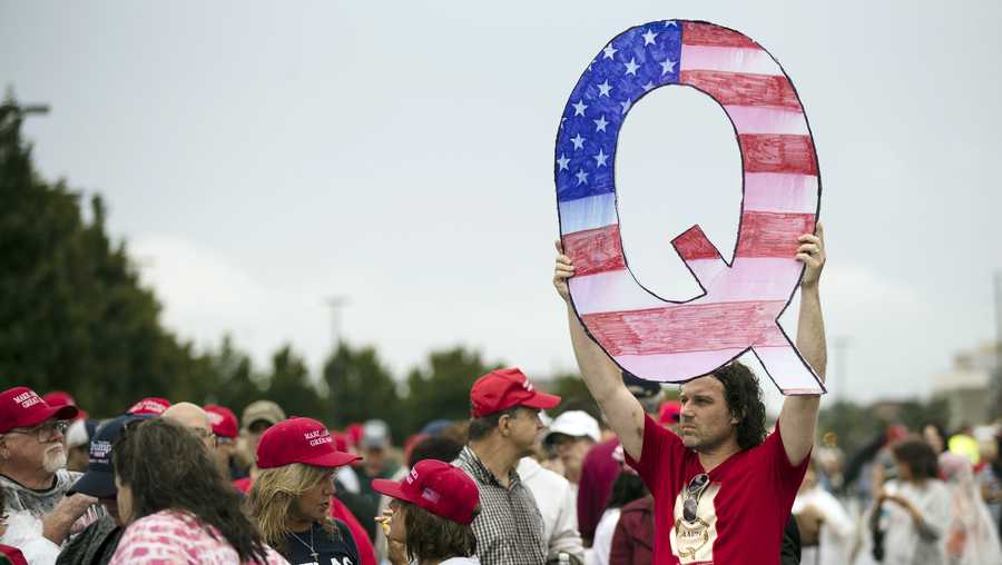 In this Aug. 2, 2018, file photo, a protesters holds a Q sign waits in line with others to enter a campaign rally with President Donald Trump in Wilkes-Barre, Pa.