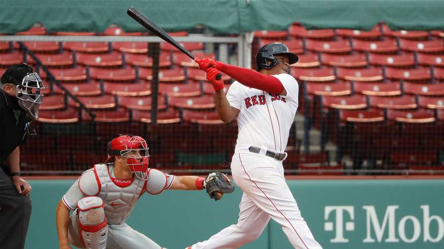 Boston Red Sox's Rafael Devers follows through on a two-run home run as Philadelphia Phillies catcher J.T. Realmuto looks on during the third inning of a baseball game Wednesday, Aug. 19, 2020, at Fenway Park in Boston. (AP Photo/Winslow Townson)