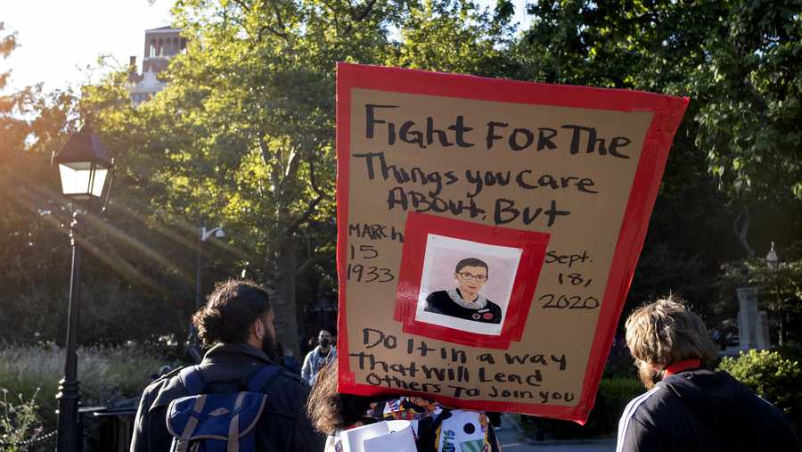 In this Saturday, Sept. 19, 2020, file photo, a sign featuring a likeness of Justice Ruth Bader Ginsburg is carried in Washington Square Park in New York, a day after the death of the Supreme Court justice.