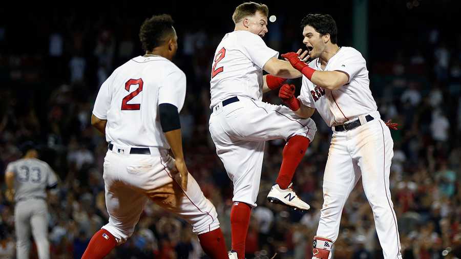 Boston Red Sox's Andrew Benintendi, right, celebrates his game-winning RBI single with Brock Holt, center, and Xander Bogaerts (2) during the tenth inning of a baseball game against the New York Yankees in Boston, Monday, Aug. 6, 2018