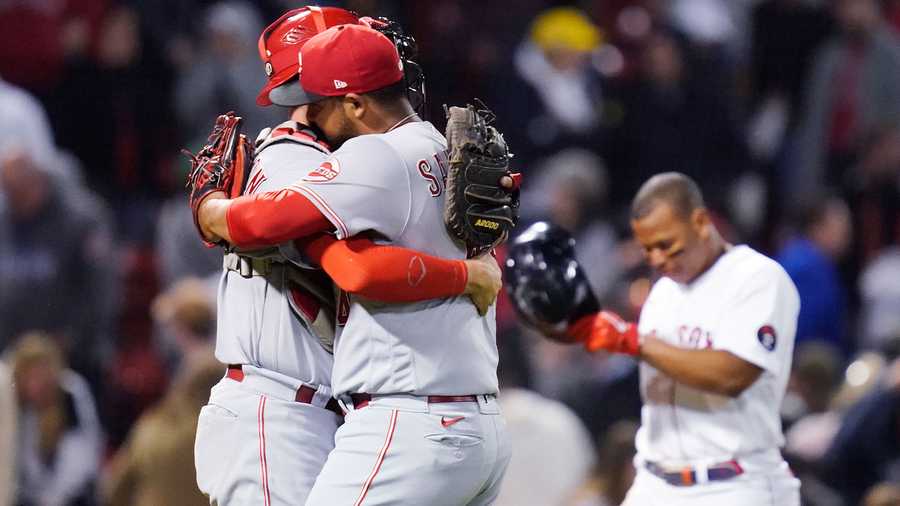 Cincinnati Reds' Tony Santillan, front right, is embraced by catcher Tyler Stephenson after the Reds defeated the Boston Red Sox 2-1 in a baseball game Tuesday, May 31, 2022, at Fenway Park in Boston. At right rear is Red Sox's Rafael Devers.