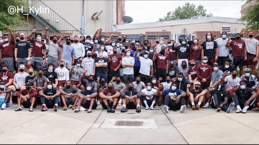 MSU football players poise for a picture after sitting out of practice to focus on change