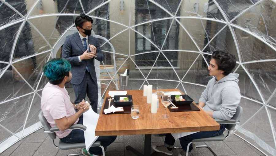 Waiter Masaaki Shijeno explains to diners (left to right) Al Habeeb and Ed Shehab what their first course will consist of. Sushi Hashiri opened up outdoor dining service using patio bubbles in front of their restaurant in San Francisco on Aug. 5, 2020.