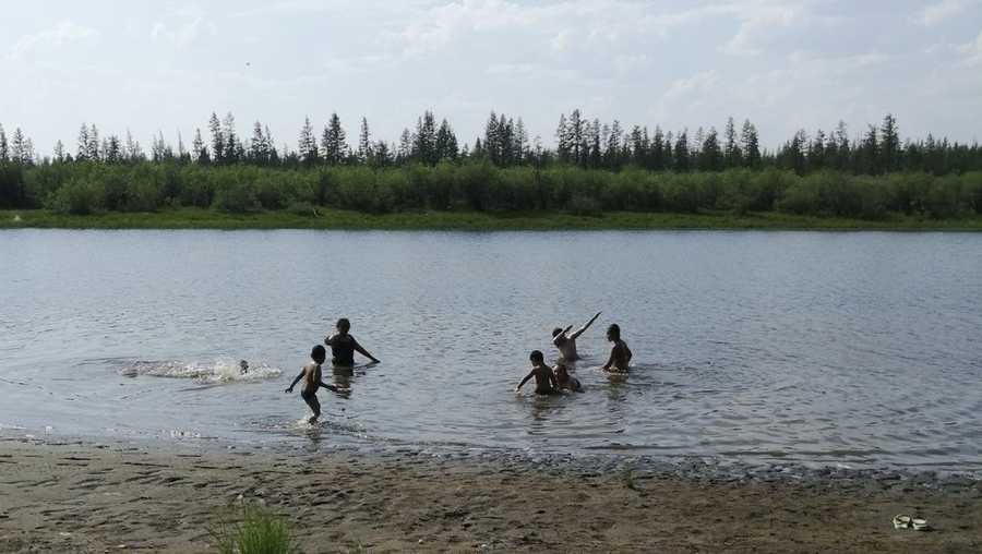 In this handout photo provided by Olga Burtseva, children play in the Krugloe lake outside Verkhoyansk, the Sakha Republic, about 2900 miles northeast of Moscow, Russia, Sunday, June 21, 2020. A Siberian town that endures the world's widest temperature range has recorded a new high amid a hear wave that is contributing to severe forest fires.