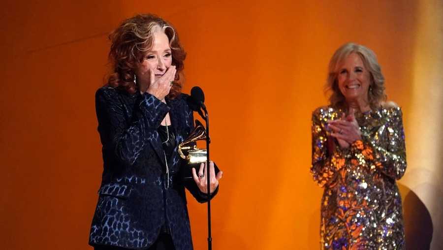 a surprised bonnie raitt accepts the grammy for song of the year as she is applauded by first lady jill biden, who presented the award.
