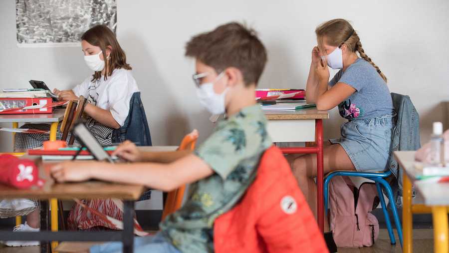 Pupils wearing fabric masks listen to their teacher as they respect social distancing on June 2, 2020.