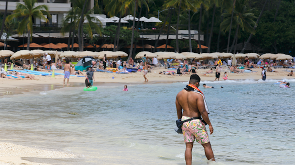 A man stands on a crowded Waikiki Beach in Honolulu, Monday, May 23, 2022.