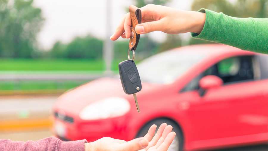 car sales. one person sells car and gives the key to the new owner