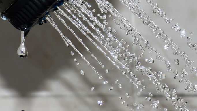A showerhead is shown with water spraying out.