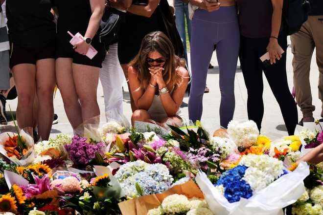 A woman kneels and prays at a flower memorial to shooting victims outside the Bondi Pavilion at Sydney's Bondi Beach.