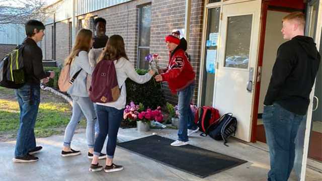 Jayme Wooley hands flowers to students entering their school in Texas for Valentine's Day