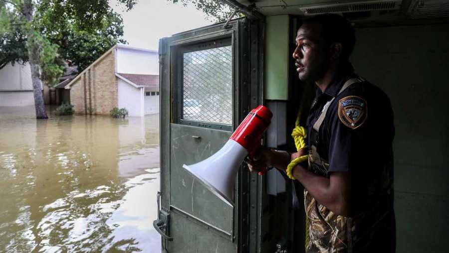Sheriff's Deputy Rick Johnson pauses to listen for people's voices Wednesday while searching for flood victims in a neighborhood inundated by water from the Addicks Reservoir in Houston.  
