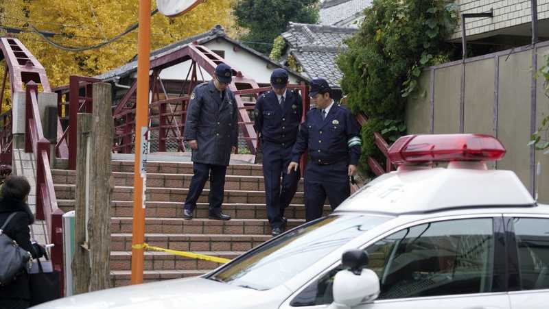 Police officers walk near the scene of a stabbing incident at Tomioka Hachimangu shrine in Tokyo Friday, Dec. 8, 2017. Police say three people have died in the stabbing attack on Thursday night at the prominent shrine, including the head priest and the attacker, who apparently took his own life. 