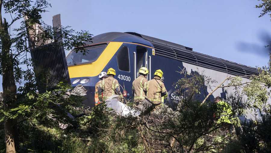 Emergency services attend the scene of a derailed train in Stonehaven, Scotland, Wednesday Aug. 12, 2020. Police and paramedics were responding Wednesday to a train derailment in northeast Scotland, where smoke could be seen rising from the site. Officials said there were reports of serious injuries. The hilly area was hit by storms and flash flooding overnight.