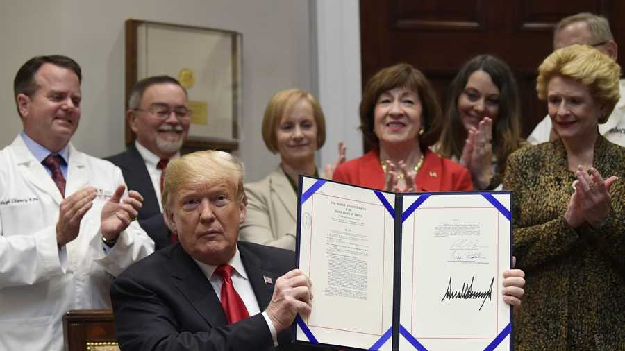 President Donald Trump holds up the 'Patient Right to Know Drug Prices Act' after signing it and the 'Know the Lowest Price Act of 2018,' during a ceremony in the Roosevelt Room of the White House in Washington, Wednesday, Oct. 10, 2018. 