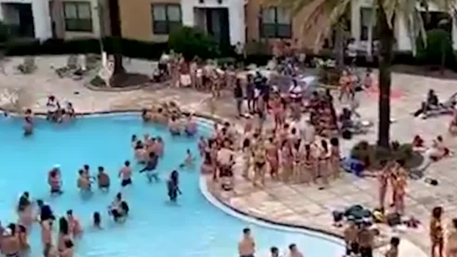 Photo shows people gathering near a pool at an apartment complex near UCF.
