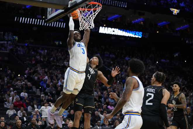 UCLA's Eric Dailey Jr., left, goes up for a dunk past UCF's Jamichael Stillwell during the first half in the first round of the NCAA college basketball tournament, Friday, March 20, 2026, in Philadelphia.