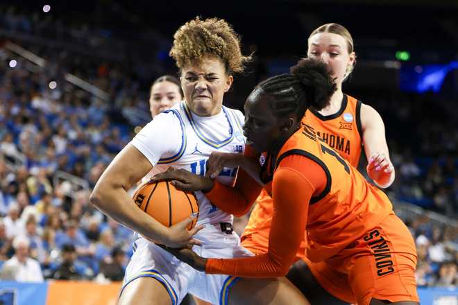 UCLA guard Kiki Rice, front left, and Oklahoma State forward Achol Akot, front right, battle for the ball as Oklahoma State guard Amari Whiting, back right, watches during the first half in the second round of the NCAA college basketball tournament, Monday, March 23, 2026, in Los Angeles.