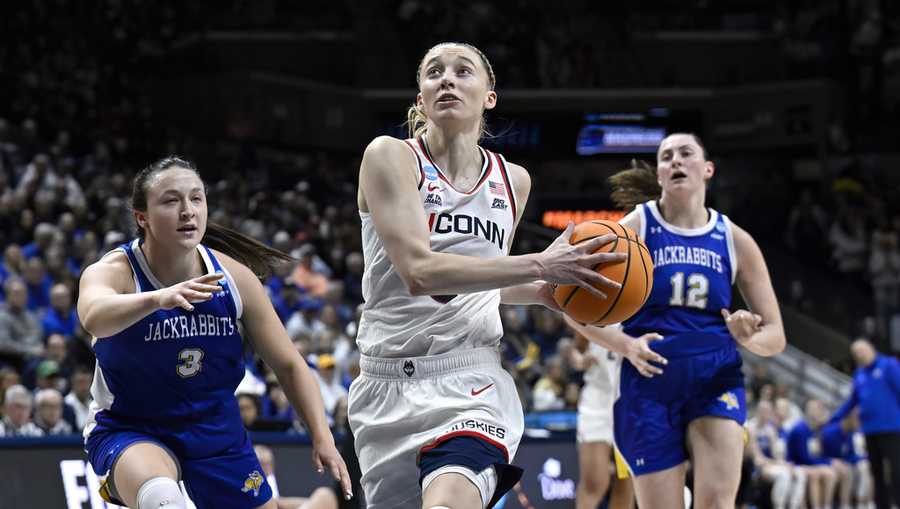 UConn guard Paige Bueckers, center, drives to the basket as South Dakota State guard Madison Mathiowetz, left, defends during the second half of a second round of the NCAA college basketball tournament.