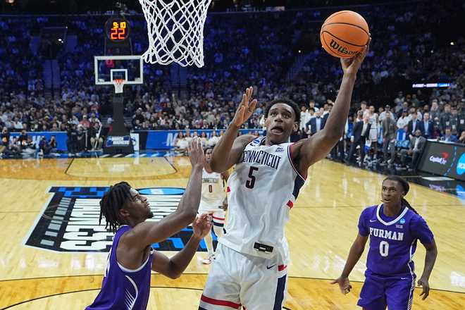 UConn's Tarris Reed Jr. (5) goes up to shoot against Furman's Cooper Bowser, left, during the first half in the first round of the NCAA college basketball tournament, Friday, March 20, 2026, in Philadelphia.