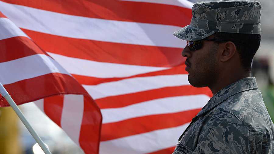 A member of the United States Air Force stands on the grid with an American flag prior to the NASCAR Sprint Cup Series AAA 400 at Dover International Speedway on September 29, 2013 in Dover, Delaware.