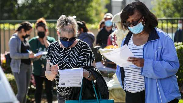 Maureen Brackett, 70, left, and Beulah Knowles, 77, fill out medical forms while waiting in line for coronavirus vaccine at a COVID-19 vaccine clinic held by L.A. County Department of Public Health for seniors at Whispering Fountains Senior Living Community on Wednesday, March 31, 2021 in Lakewood, CA.