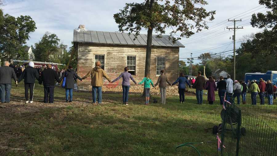 Community members form a unity circle around the school, where they gathered in early October to repair damage done by vandals.