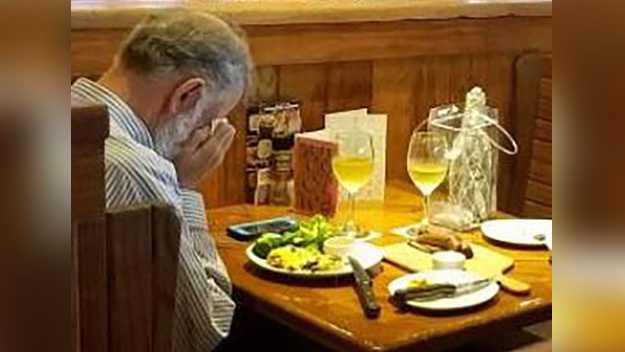 A man holds his face as he has a Valentine's Day meal with his wife's ashes on Feb. 14, 2018.