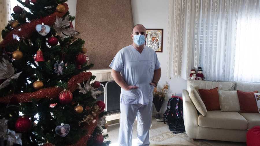 In this Saturday, Dec. 12, 2020 photo, Gabriel Tachtatzoglou poses at his home in Agios Athanassios, outside Thessaloniki city, northern Greece. Tachtatzoglou has worked as an ICU nurse in northern Greece for 20 years but when the pandemic struck his city in the fall, COVID-19 wards were quickly overwhelmed. He saw little choice other than to treat sick members of his family at home, setting up a treatment site with borrowed and rented medical machinery and using a hat stand to hold IV bags.