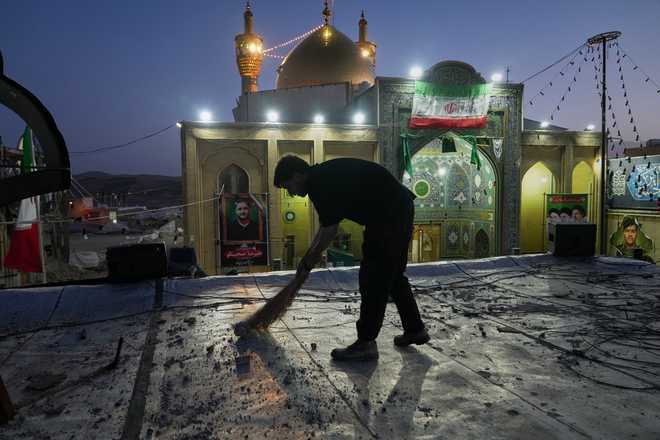 A worker cleans an area within the Grand Hosseiniyeh complex, with the mosque visible in the background, that officials say was hit by U.S.-Israeli airstrikes Tuesday in Zanjan, Iran, Saturday, April 4, 2026.