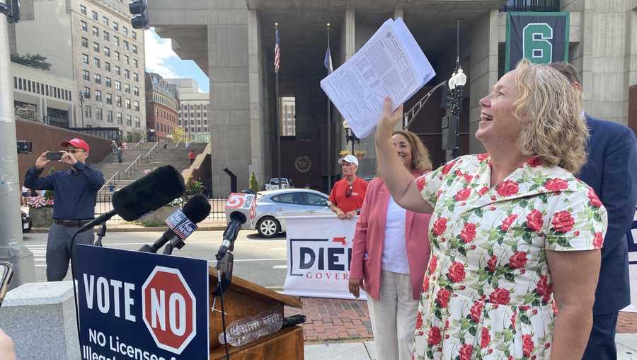 wendy wakeman of fair & secure ma holds up some of the 100k petition signatures the group says it collected.
